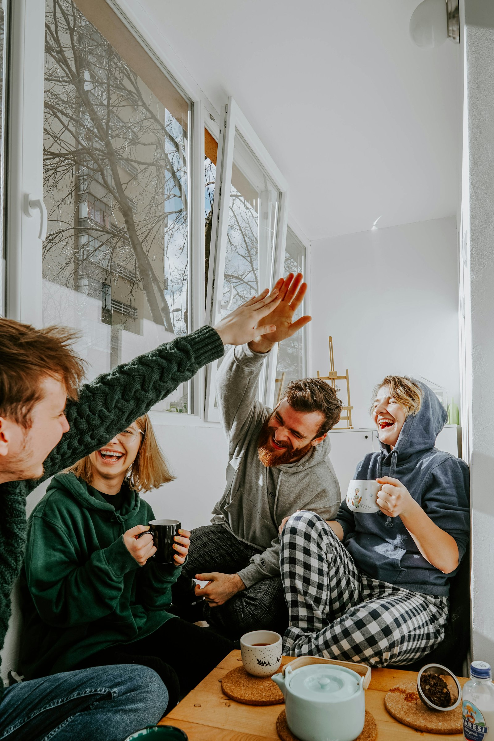 Con chi mangiare Milano – quattro amici che ridono e si danno il cinque davanti a un caffe