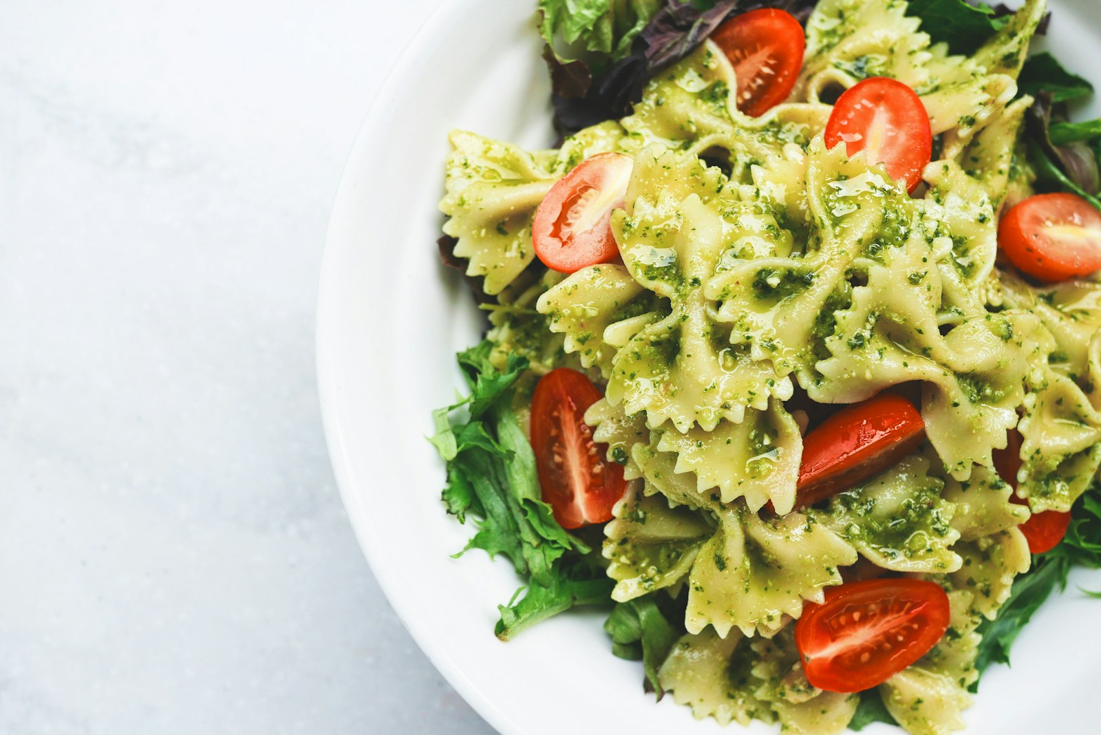 Precotto, Turro, Gorla Milano – pasta al pesto con pomodori a fette servita su piatto di ceramica bianca